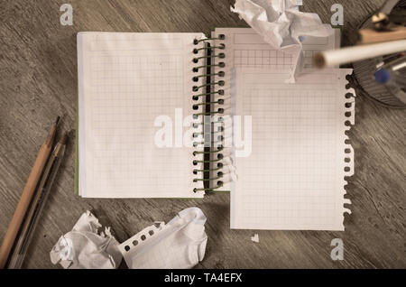 Empty crumpled pages and notebook lying on wooden surface Stock Photo