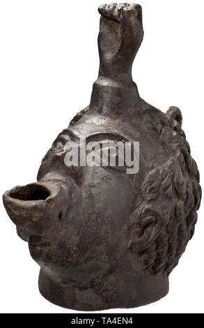 A Roman oil lamp shaped like an African head, 2nd - 3rd century Bronze lamp, the opening of which is fashioned as the pouting mouth of an African man. In combination with the bulging eyes and a hollow fist emerging from the forehead, the whole piece has a grotesque appearance. The hair styled in cropped, curly locks. The lid is missing on the back of the head, one hinge bracket still in place. Rare version of a common type with a fist on the forehead. Dark green patina. Length 9.6 cm, height 10.3 cm. Provenance: Viennese private collection, acqui, Additional-Rights-Clearance-Info-Not-Available Stock Photo