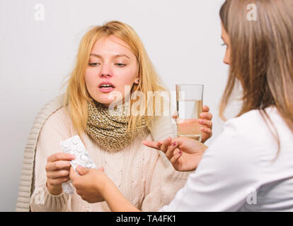 Recognize symptoms of cold. Remedies should help beat cold fast. Woman consult with doctor. Girl in scarf hold tissue while doctor offer treatment. Cold and flu remedies. Tips how to get rid of cold. Stock Photo