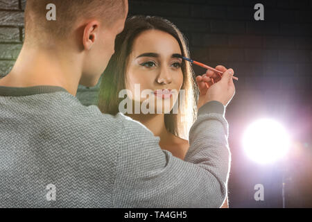 Professional makeup artist working with young model in photo studio Stock Photo