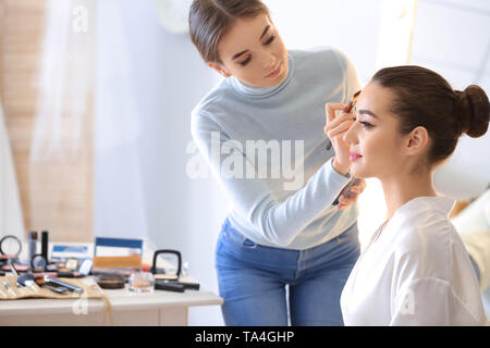 Professional makeup artist working with young bride at home Stock Photo