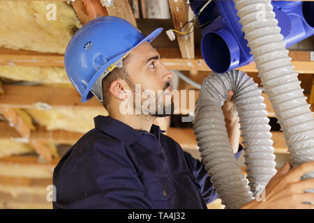 plumber checking ceiling pipes Stock Photo