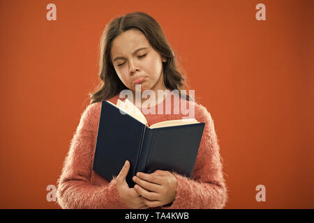 Girl hold book read story over orange background. Child enjoy reading book. Book store concept. Wonderful free childrens books available to read. Childrens literature. Sad ending story. Stock Photo