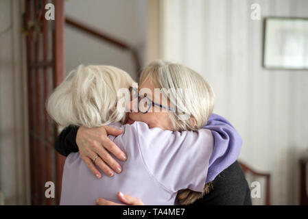 Mother does not want her daughter to leave-After a visit to see her elderly and sight impaired mother,the daughter hugs and says goodbye to her mom, b Stock Photo
