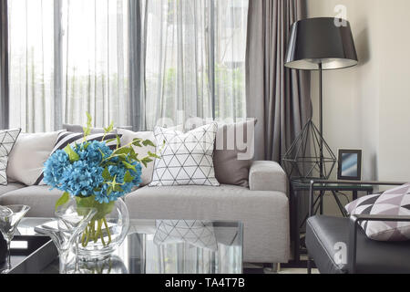 Varies pattern pillows in monotone setting on light gray sofa with black standing lamp Stock Photo