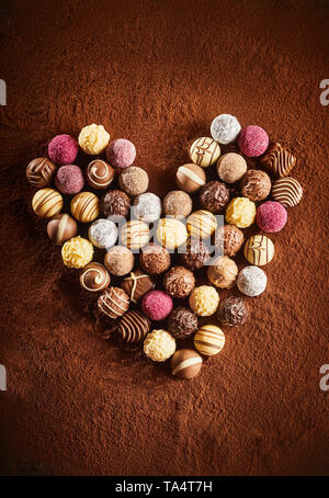 Romantic heart shaped chocolate still life on a background of cocoa powder with delicious handmade round decorated candy Stock Photo