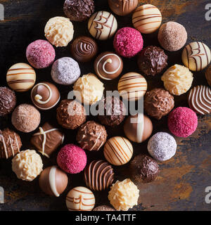 Gourmet speciality chocolate bonbons or pralines arranged in a neat rectangle on rustic wood table viewed top down Stock Photo