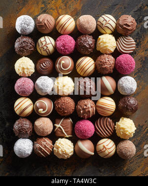 Neat flat lay of luxury chocolate pralines or bonbons arranged in a rectangle in rows displaying a wide selection of decorative patterns and textures  Stock Photo