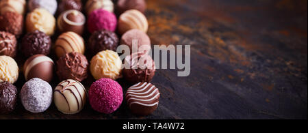 Panorama banner of assorted decorative handmade luxury chocolate balls on textured rustic or vintage wood with copy space Stock Photo