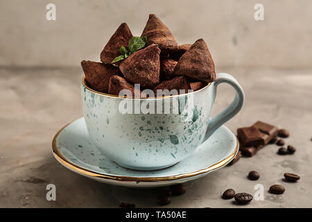 Cup with tasty sweet truffles on grey table Stock Photo