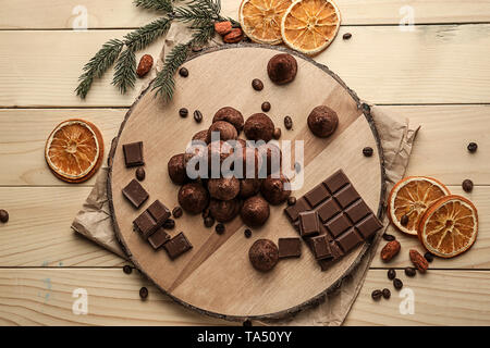 Board with tasty sweet truffles and chocolate on wooden table Stock Photo