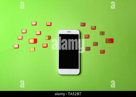 Mobile phone and many sim cards on color background Stock Photo