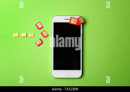 Mobile phone and arrow made of sim cards on color background Stock Photo