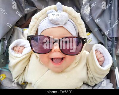 Funny face of baby, happiness girl with sunglasses is laughing, Ukraine Stock Photo