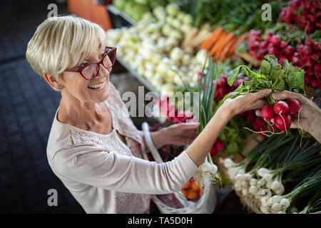 Senior woman buying vegetables at the green market. Stock Photo