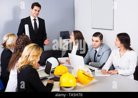 Team of engineers discussing business project and smiling in office Stock Photo