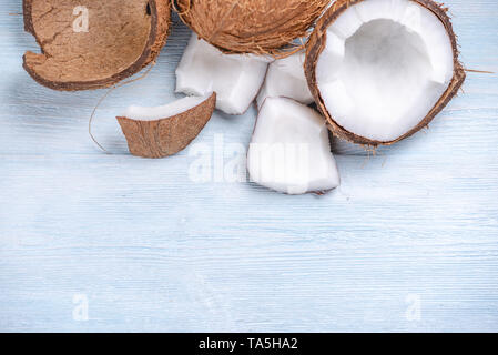 Open coconut with white pulp on blue wooden background. Organic healthy vegan product widely used in cosmetics Stock Photo