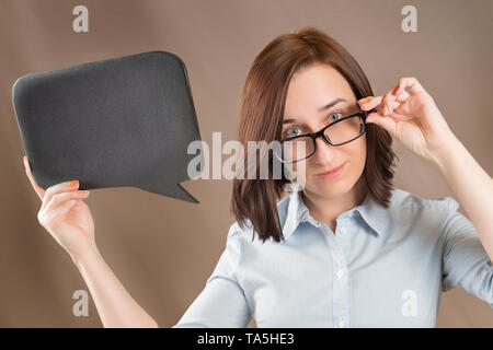 Woman in glasses holding blank black slate with copy space. Short message, question and announcement theme. Stock Photo