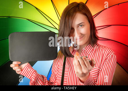 Happy woman on rainbow colored background with watch and empty sign board. Stock Photo