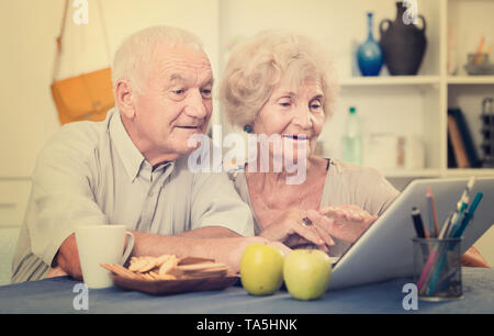 Portrait of cheerful mature spouses using laptop at home Stock Photo