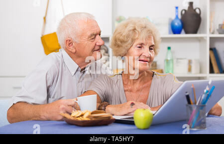Portrait of cheerful mature spouses using laptop at home Stock Photo