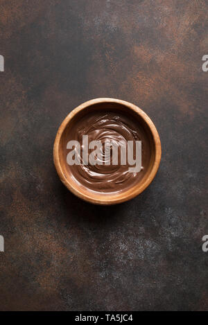Chocolate Spread on dark background, top view, copy space. Homemade melted chocolate in bowl. Stock Photo