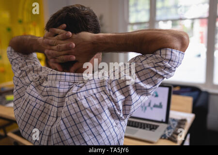 Male executive working with hands behind head at desk in office Stock Photo
