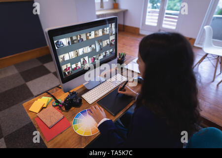 Woman graphic designer using a graphic tablet and a computer at her desk Stock Photo