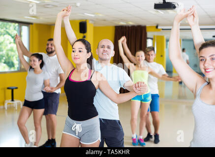 Positive couples of adults practicing salsa in modern dance studio Stock Photo