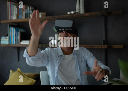 Mature man using virtual reality headset in living room Stock Photo