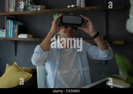 Mature man using virtual reality headset in living room Stock Photo