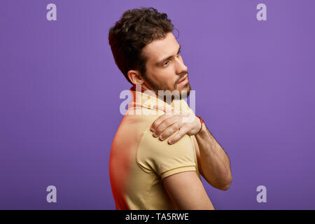 attractive man suffering from pain in his shoulder. close up side view photo.guy massaging his shoulder, medicine concept Stock Photo