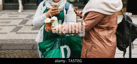 Two girls and schoolgirls or students take pictures of a traditional Czech dessert called Trydlo for a post in a social network. Stock Photo