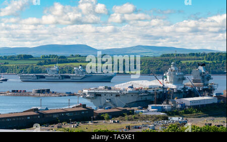 Rosyth, Scotland, UK. 22nd May, 2019. Aircraft carrier HMS Queen Elizabeth moored off Rosyth in the River Forth after leaving dry dock yesterday after a visit to her home port. She will leave the Forth today and return to sea in preparation for Westlant 19 deployment which is designed to focus on the operations of her F-35 fighter aircraft. Pictured; Rare view of both of the Royal Navy's aircraft carriers. HMS Queen Elizabeth on left and HMS Prince of Wales still under construction in shipyard at Rosyth. Credit: Iain Masterton/Alamy Live News Stock Photo