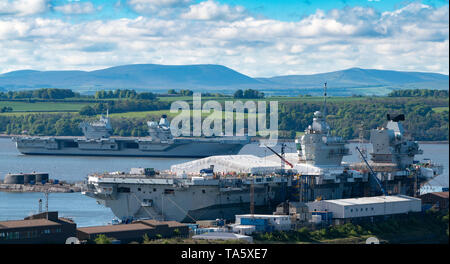 Rosyth, Scotland, UK. 22nd May, 2019. Aircraft carrier HMS Queen Elizabeth moored off Rosyth in the River Forth after leaving dry dock yesterday after a visit to her home port. She will leave the Forth today and return to sea in preparation for Westlant 19 deployment which is designed to focus on the operations of her F-35 fighter aircraft. Pictured; Rare view of both of the Royal Navy's aircraft carriers. HMS Queen Elizabeth and in foreground HMS Prince of Wales still under construction in shipyard at Rosyth. Credit: Iain Masterton/Alamy Live News Stock Photo