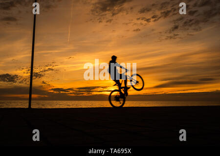 Aberystwyth Wales UK, Wednesday 22 May 2019  UK Weather: People silhouetted  cycling along the seafront promenade at sunset in Aberystwyth on a mild May evening, at the end of a day of warm spring sunshine on the west coast of Wales. photo credit: Keith Morris / Alamy Live News Stock Photo