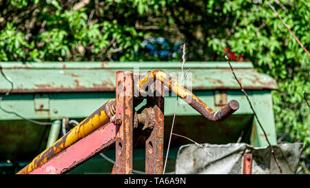 Parts of an old and abandoned agricultural machinery in a corner of an agricultural farm, rusty and old metal from a cultivator, sunny day in the coun Stock Photo