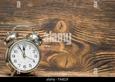 Retro alarm clock on a wooden background shows 12 hours, the space is right Stock Photo