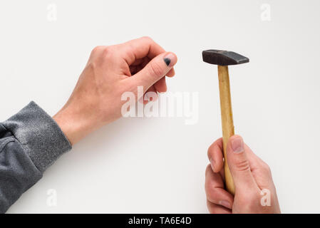 Hammer on the finger. Black thumbnail. Injury in violation of occupational safety. Men hands on white background Stock Photo