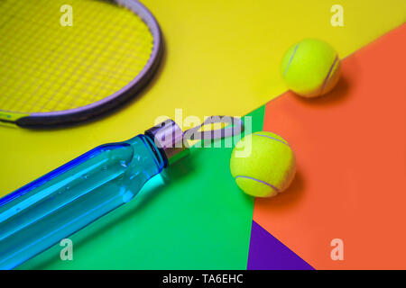Tennis layout with tennis balls, racket, bottle of water on abstract different multicolored neon background with place for text. Stock Photo