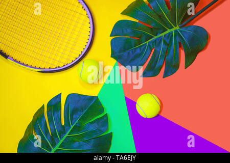 Tennis layout with tennis balls, racket and tropical monstera leaves on abstract different multicolored neon background. Stock Photo