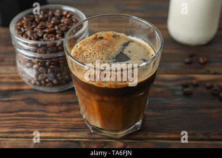 Glass of fresh coffee and coffee beans on wooden table, space for text Stock Photo