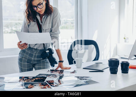 Young woman busy working in her studio. Caucasian female photographer checking prints after developing. Stock Photo