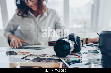 Female artist working on drawing pad at office desk while looking at image prints. Young woman retouching images. Stock Photo