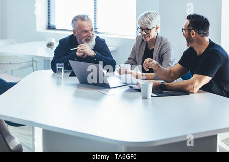 Business people discussing new business plan. Mature manager planning new strategy with colleagues in meeting. Stock Photo