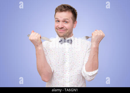 Hungry man holding fork and knife on hand to eat Stock Photo