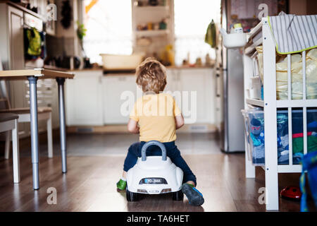 A rear view of a toddler boy with toy car playing at home. Stock Photo