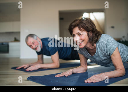 A senior couple indoors at home, doing exercise on the floor. Stock Photo