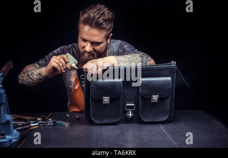 Craftsman working with leather processing a leather workpiece at a workshop Stock Photo