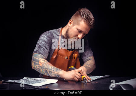Leather Craftsman processing a leather workpiece in his tanner shop Stock Photo